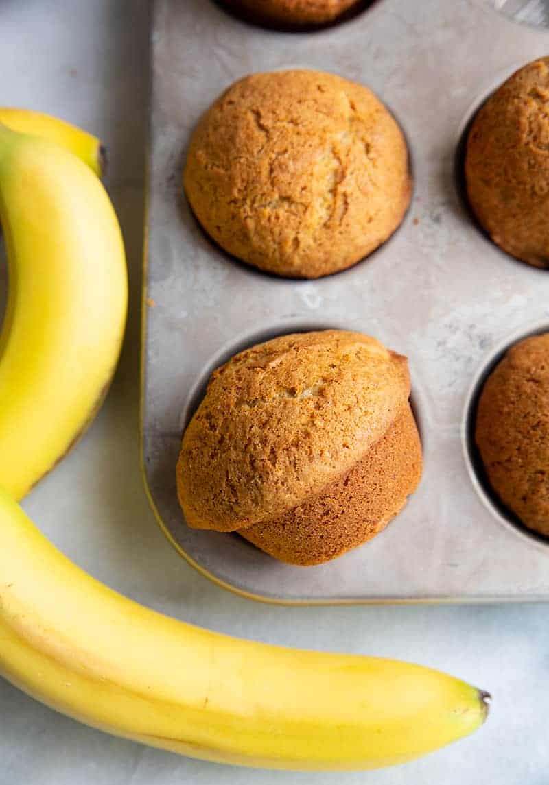 close up Banana Bread Muffins in muffin tins, rife bananas on background