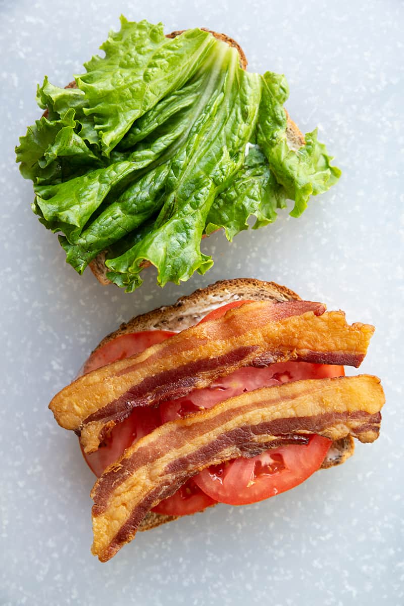 BLT Sandwich ingredients - bread toast, strips of bacon, slices of tomatoes and lettuce leaf