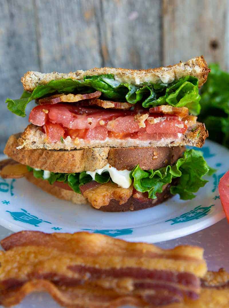 BLT Sandwich with a layer of tomatoes, bacon, and lettuce on four pieces of toast.