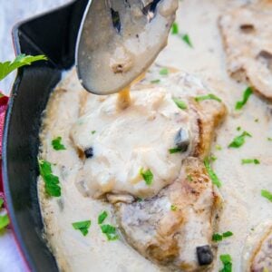 spooning mushroom soup sauce onto baked porkchops