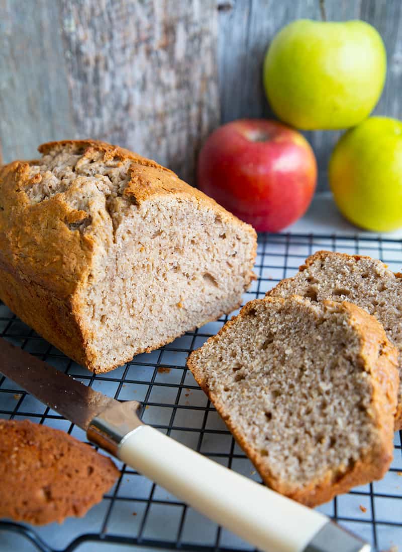 close up bread knife and sliced Cinnamon Spice Apple Bread in a wire rack, apples on background