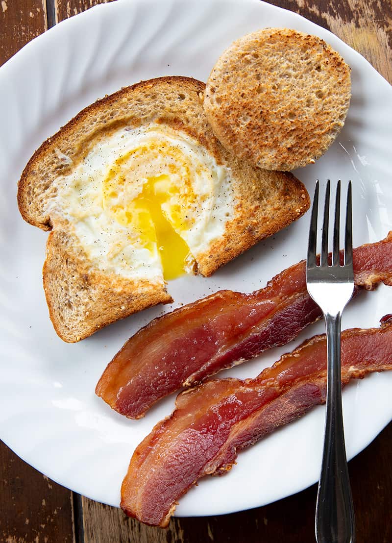 close up of Eggs in a Basket on a white plate with bacon