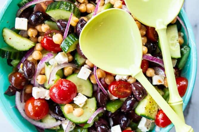 a bowl of Mediterranean Chickpea Salad with a large serving spoon and fork