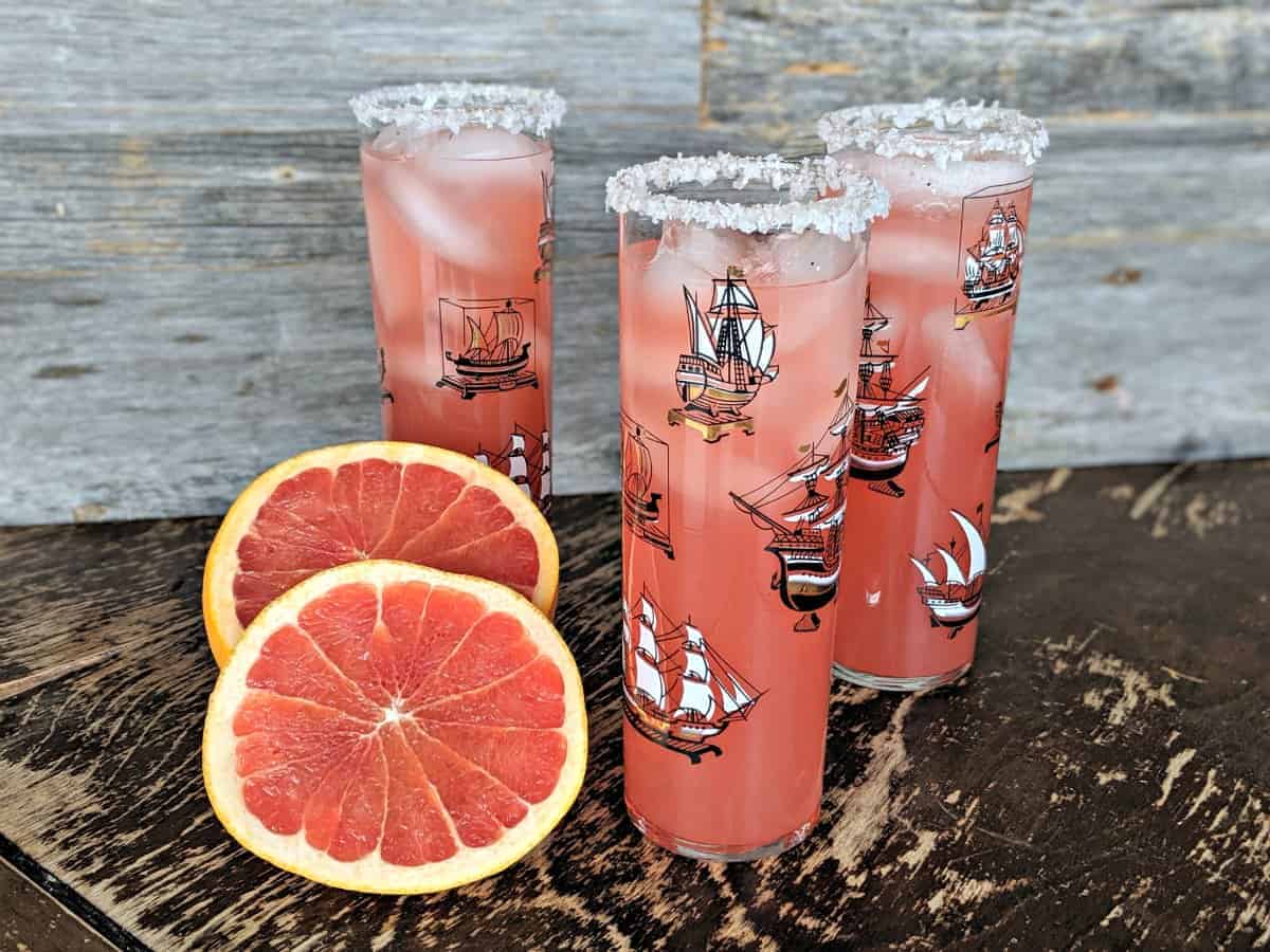 Three Salty Dog Cocktails on a table with sliced grapefruit served in Pirate Ship glasses