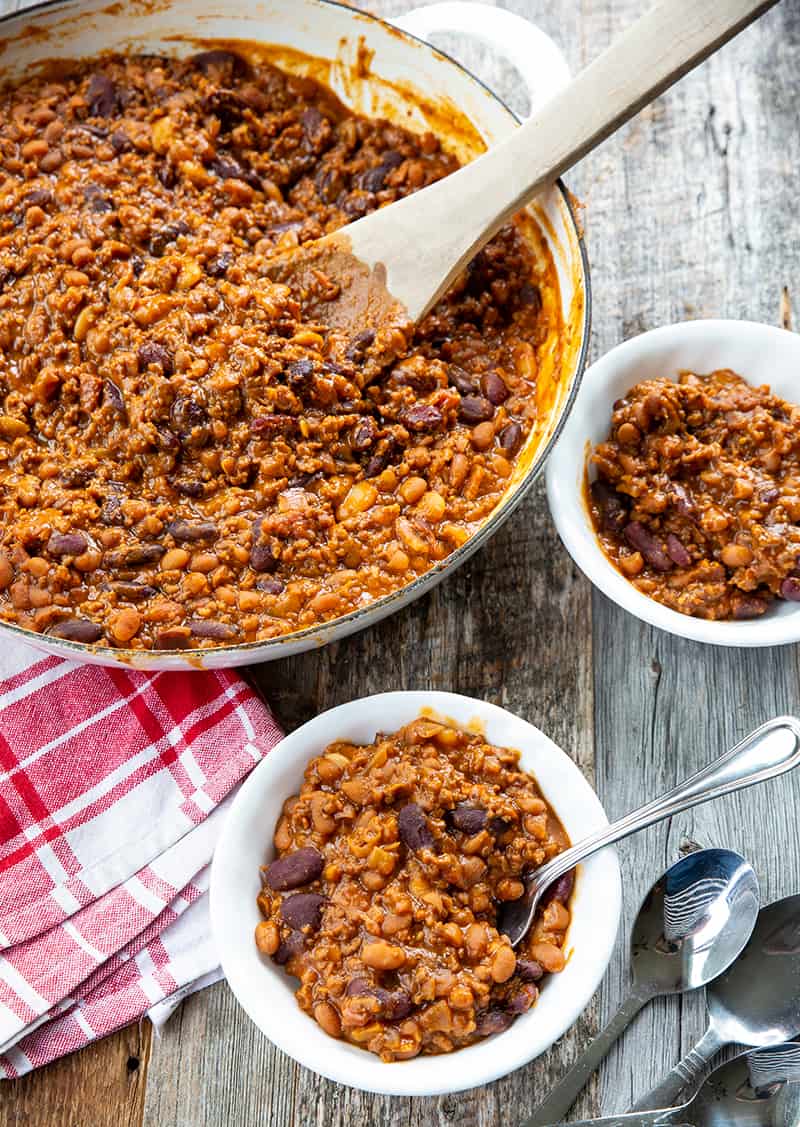 getting some serving of cowboy beans from a pot using a wooden large spoon