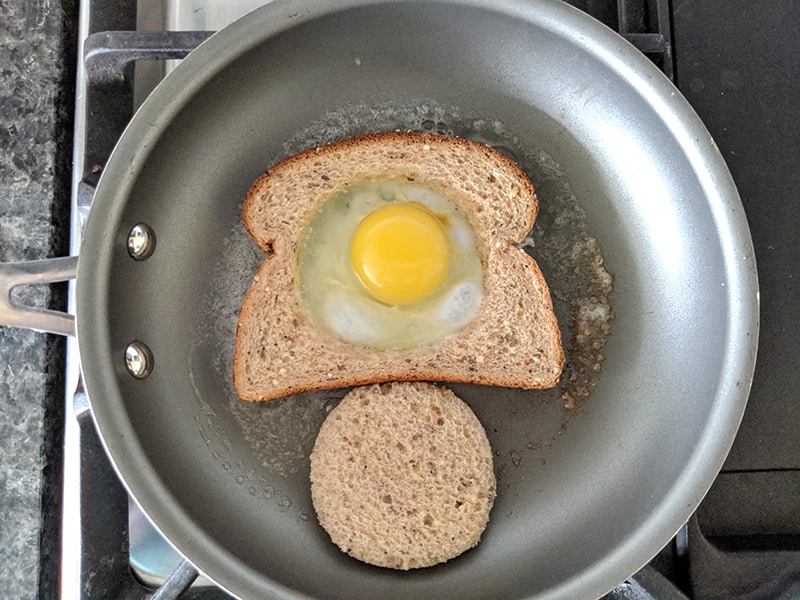 cooking Eggs in a Basket in a large frying pan with butter