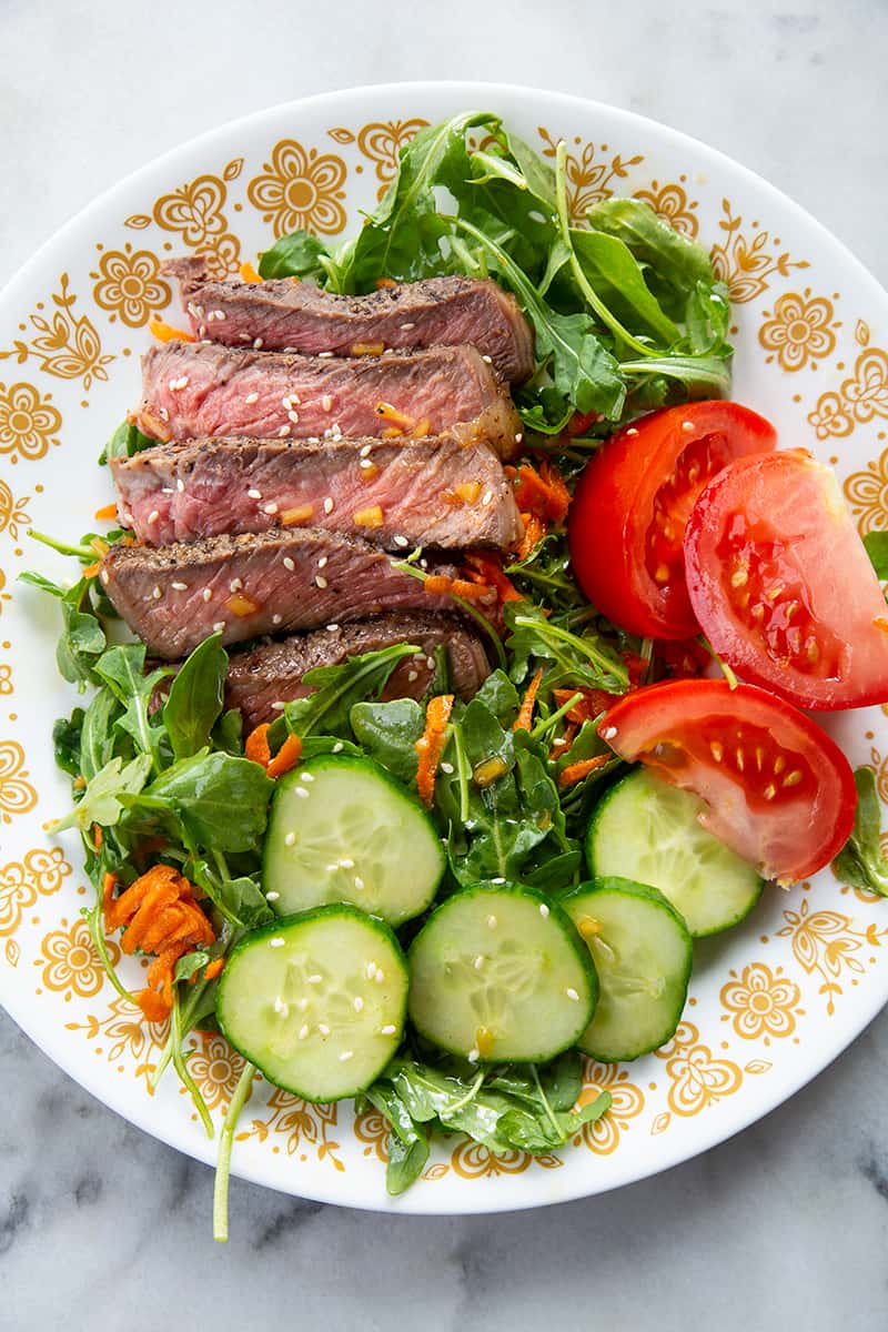 white floral designed plate with steak salad 