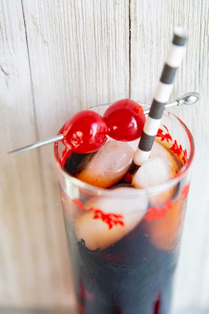 close up Roy Rogers drink in a tall vintage glass, garnished with two maraschino cherries