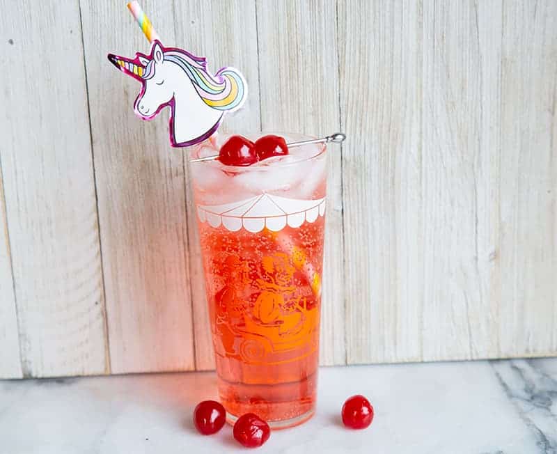 Shirley Temple drink with unicorn straw and garnish with maraschino cherries