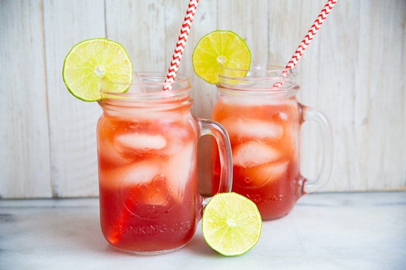 Madras Vodka Drink with red white straws on mason jars with handle, garnish with lime slices