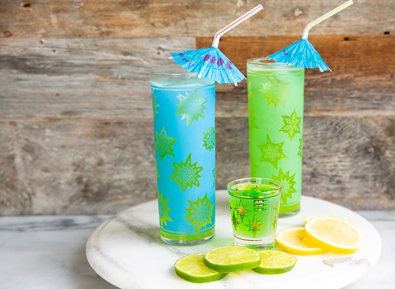 glasses of Midori Sour Cocktail garnish with Umbrella, Lemon Slice and Lime Slice