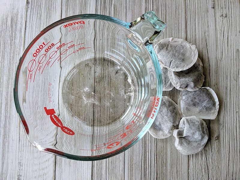 sweet tea ingredients, tea bags and measuring cup on a white board