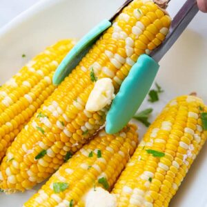 picking a Microwaved Corn on the Cob using kitchen tongs