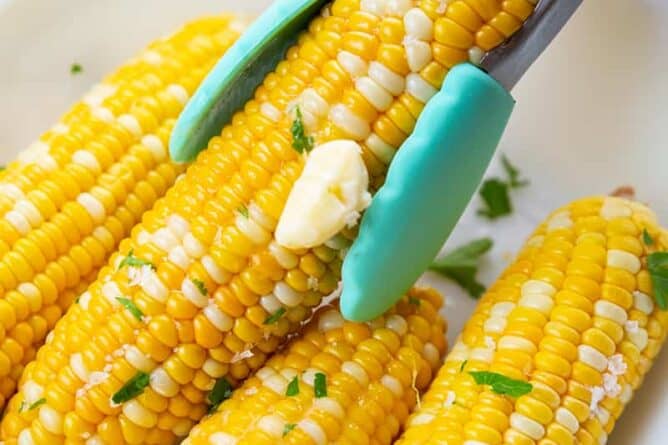 picking a Microwaved Corn on the Cob using kitchen tongs