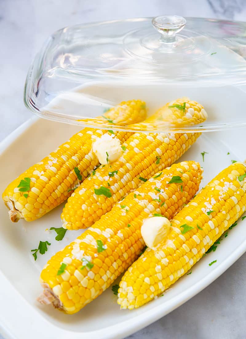 close up Microwaved Corn on the Cob with butter in a casserole dish