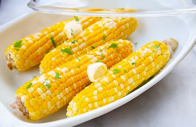 Microwaved Corn on the Cob with butter in a casserole dish