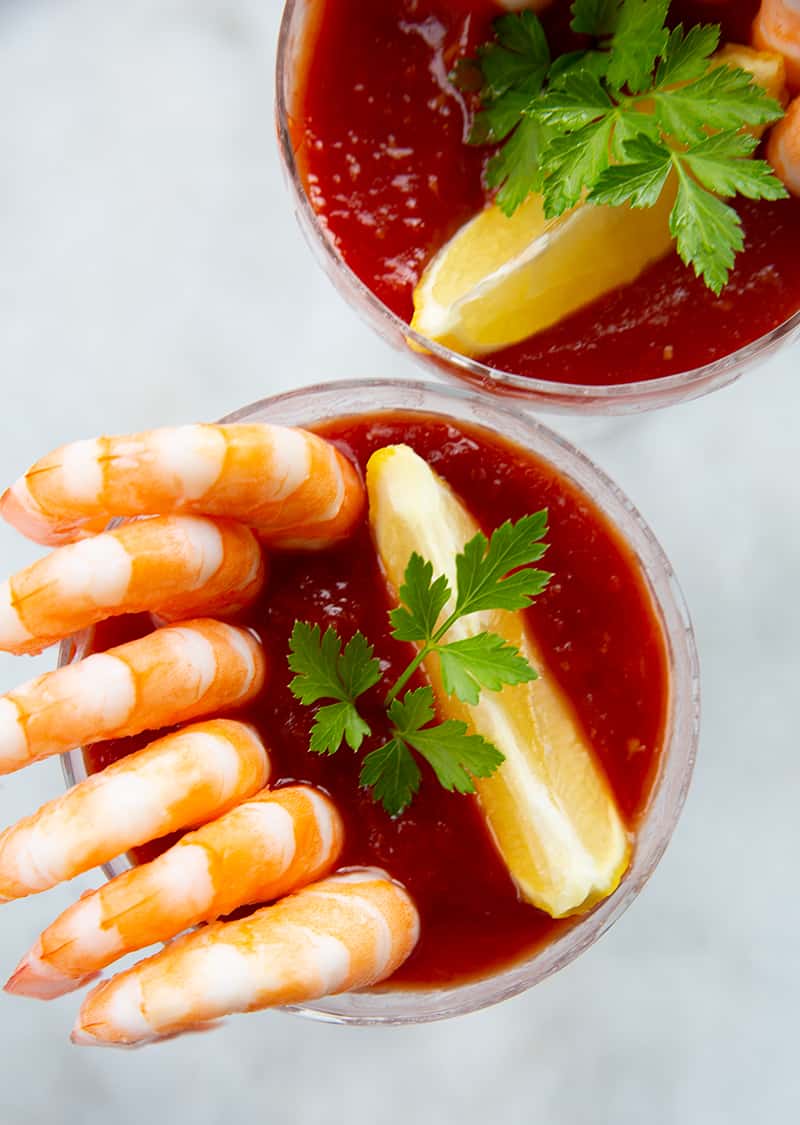 2 servings of Cocktail Sauce garnish with a slice of lemon and parsley leaves