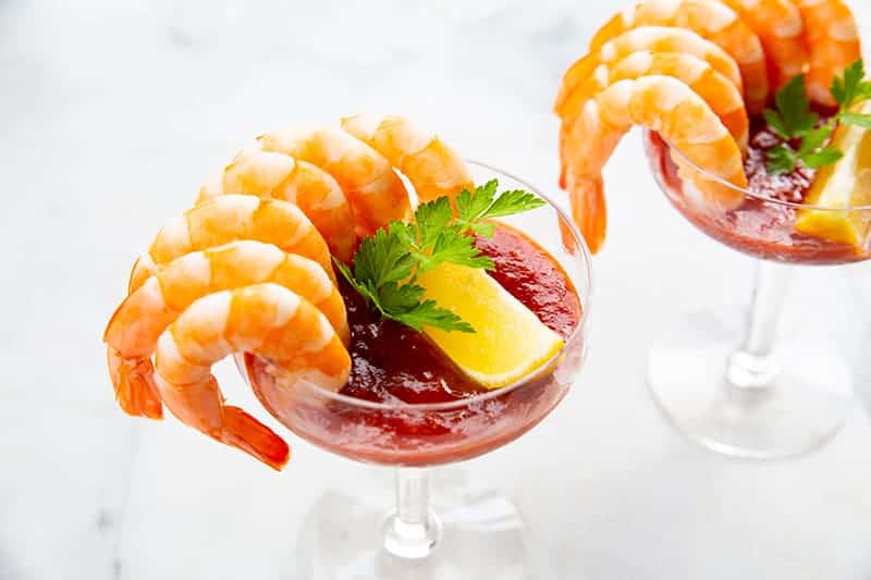 2 servings of Classic Shrimp Cocktail in sauce garnish with a slice of lemon and parsley leaves