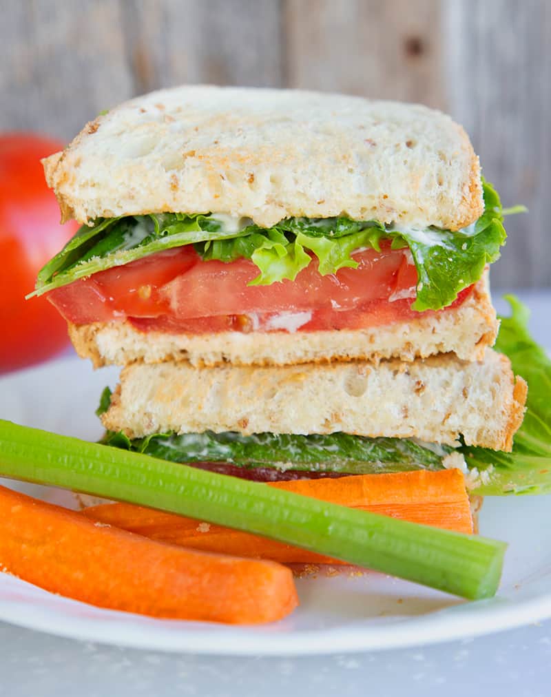 close up Classic Toasted Tomato Sandwich in a white plate. A large tomato on the background