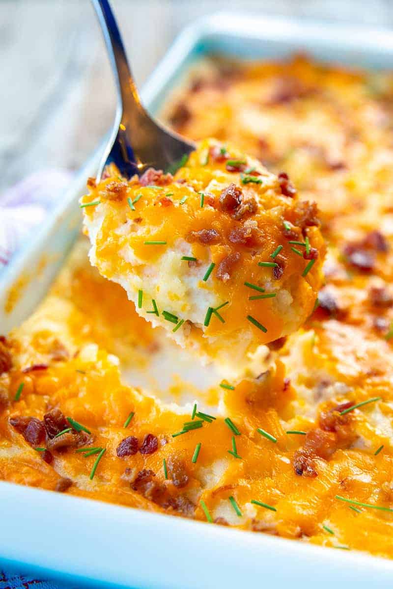 close up spoonful of Baked Cheesy Potato Casserole from a baking pan