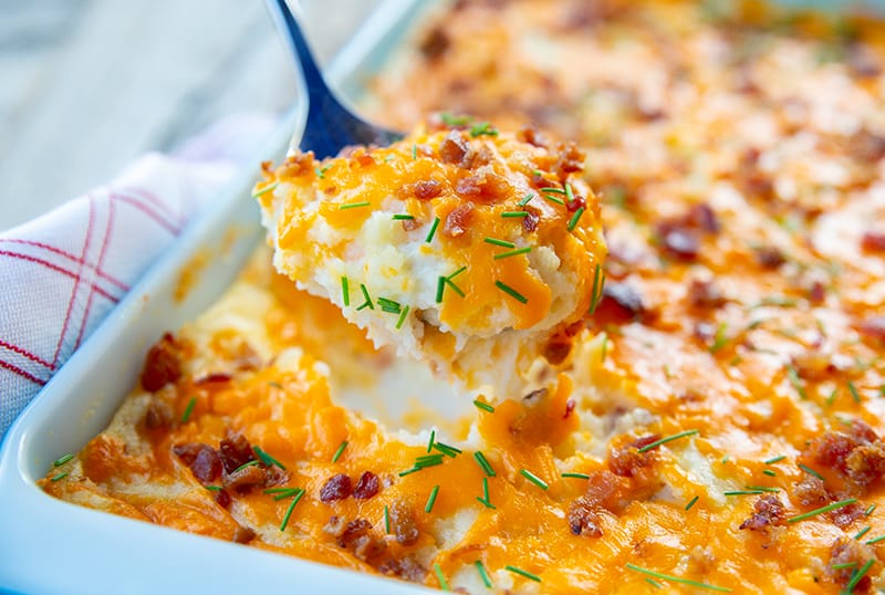 close up spoonful of Baked Cheesy Potato Casserole topped with chives and bacon