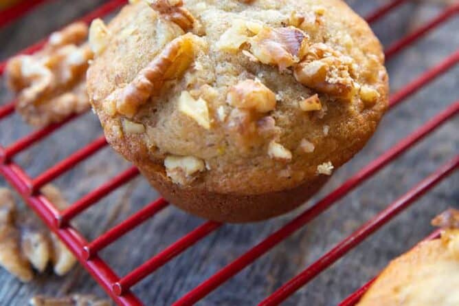 close up Banana Nut Muffins in red cooling rack, ripe bananas on its background