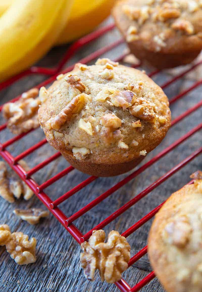 close up Banana Nut Muffin in red cooling rack, ripe bananas on its background