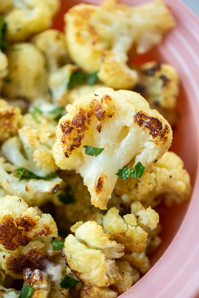 close up Buttery Garlic Roasted Cauliflower florets on pink serving bowl