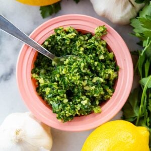 getting some Italian Gremolata from pink saucer plate using a spoon