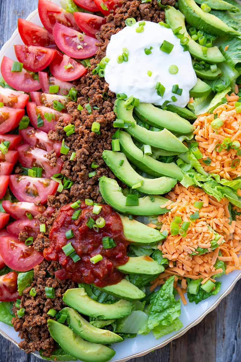 close up platter full of Ground Beef Taco Salad topped with fritos and chopped green onions