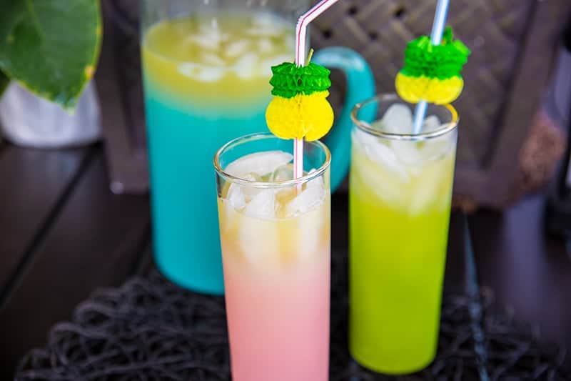 glasses of Pineapple Prosecco Party Punch with ice cubes, large pitcher with Pineapple Prosecco on the background