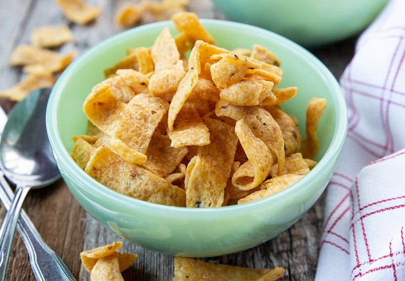 mint green bowl with Fritos corn chips, a spoon and kitchen towel beside it