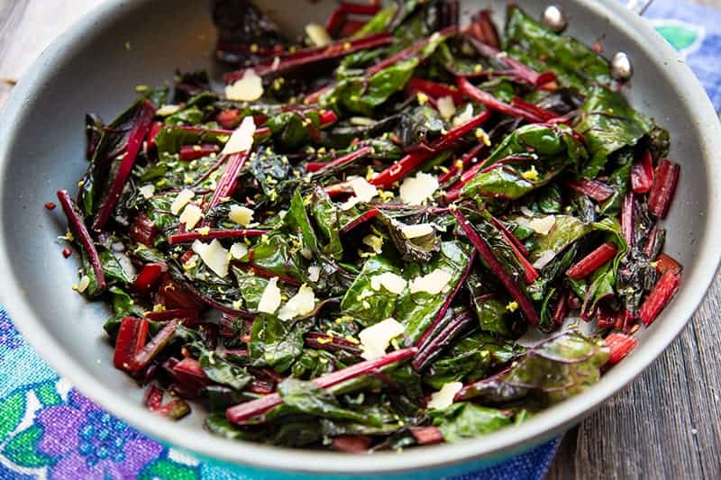 blue floral tablecloth underneath a large bowl with Lemon Parmesan Garlic Swiss Chard