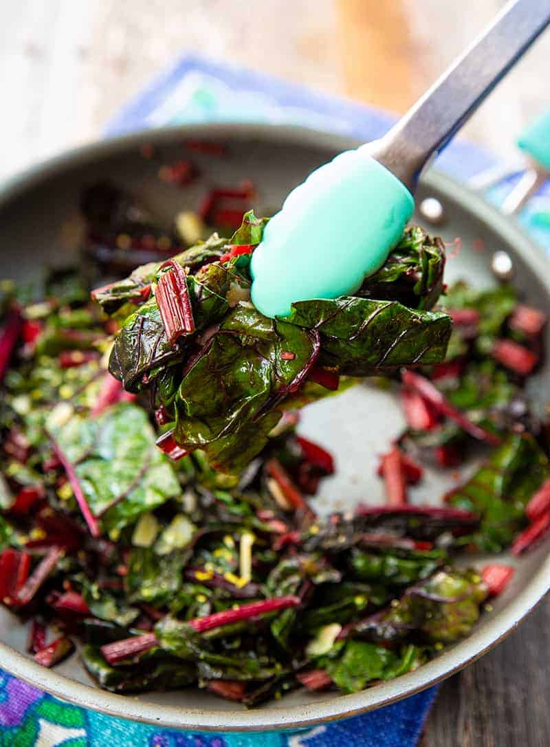 close up of Getting some Lemon Parmesan Garlic Swiss Chard using a kitchen tongs