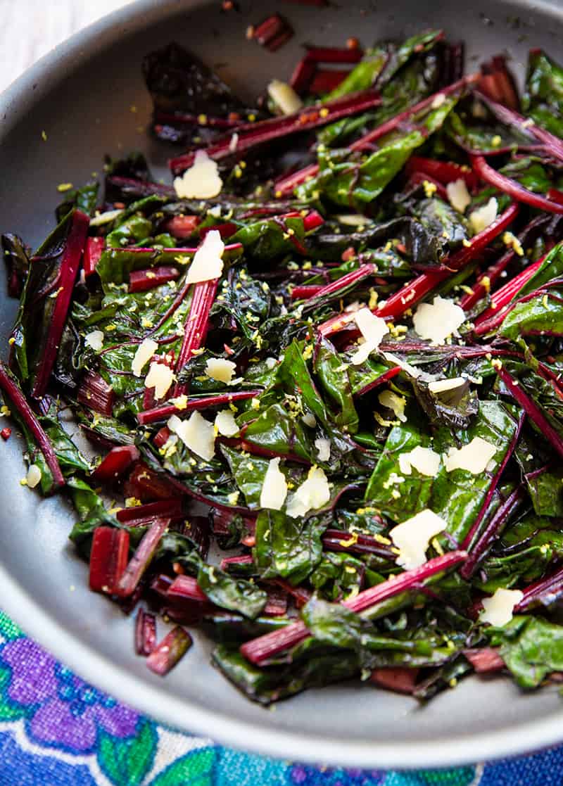 close up blue floral tablecloth underneath a large bowl with Lemon Parmesan Garlic Swiss Chard