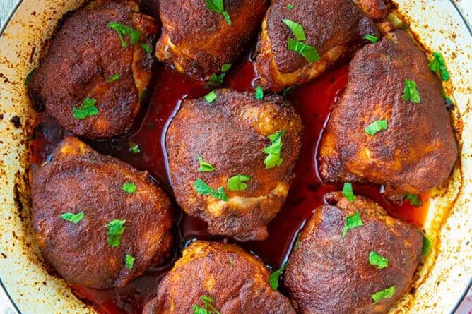 close up Smoked Paprika Baked Chicken Thighs on a white large bowl with kitchen towel underneath