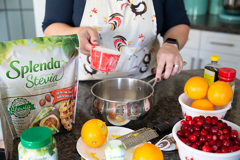 adding a cup of Splenda Stevia in a pot with water for cranberry sauce, all other ingredients on the table