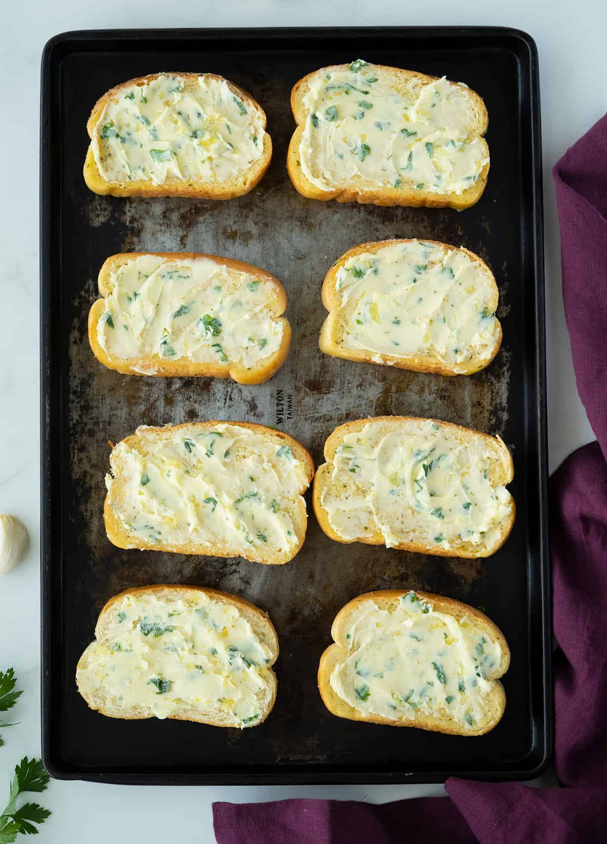 bread buttered with garlic butter on a baking sheet