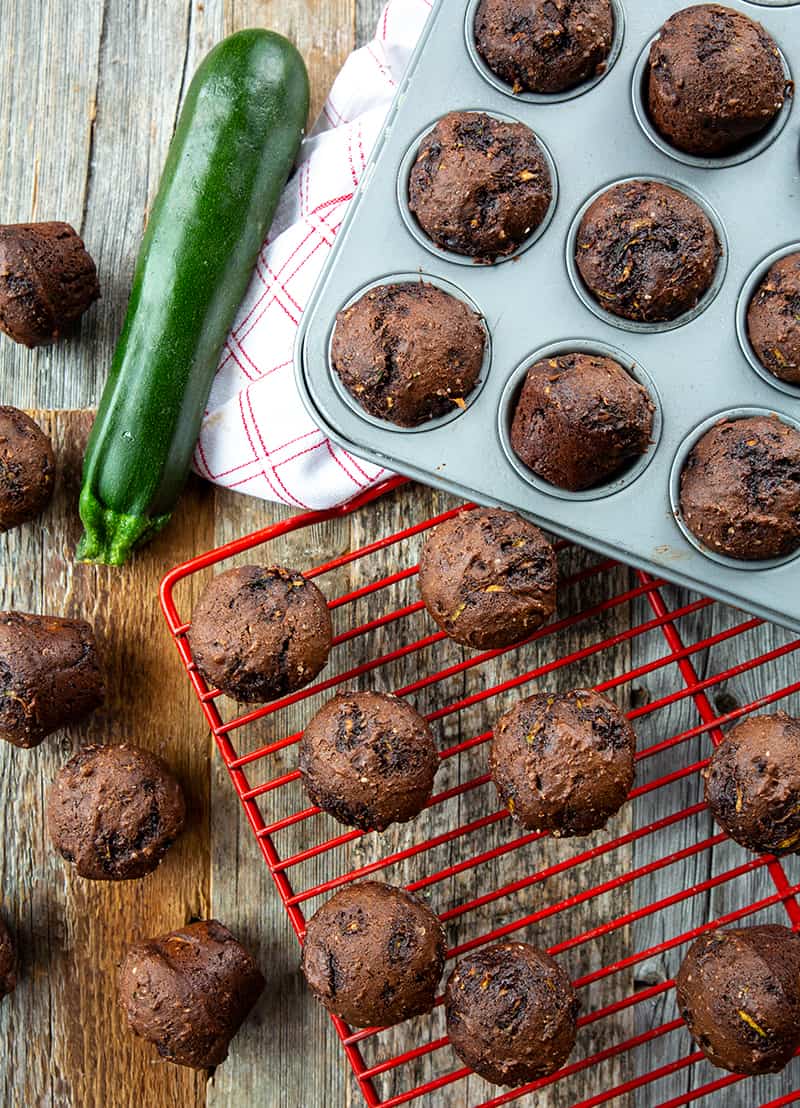 Zucchini Brownie Bites on muffin tins and red wire rack