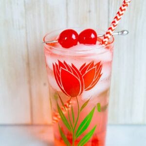 Dirty Shirley Cocktail in a glass with flower design, garnish with cherries