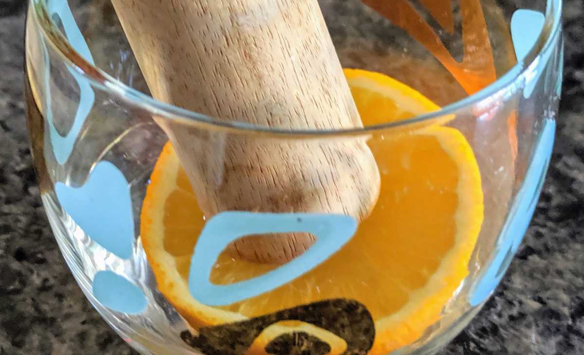 Muddling an Orange slice in a glass using a Muddler