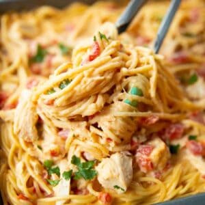 close up Cheesy Chicken Spaghetti in a pan with kitchen tongs