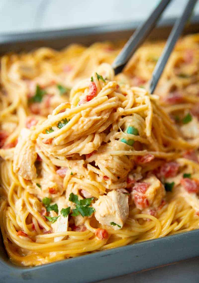 close up Cheesy Chicken Spaghetti in a pan with kitchen tongs