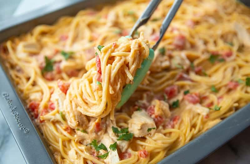 Cheesy Chicken Spaghetti in a pan with kitchen tongs