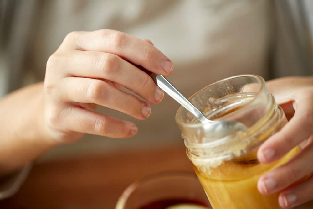 getting a spoon of honey from a jar