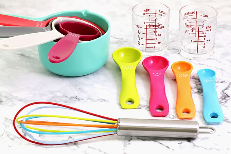 measuring and conversion cups used in kitchen and a colorful whisk tool