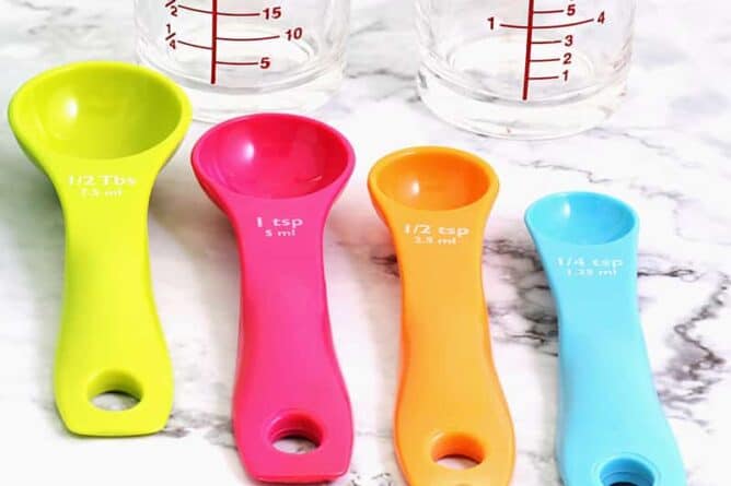 close up measuring and conversion cups used in kitchen and a colorful whisk tool