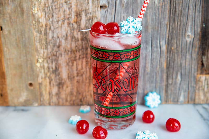 Sparkling vodka cranberry cocktail in a nice Christmas glass garnish with snowflakes and cherries
