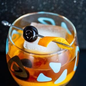 close up Old Fashioned cocktail in an old fashioned glass garnish with cherry and orange