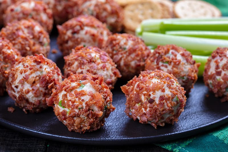 large black dinner plate with Cheese Ball rolled on bacon and celery sticks